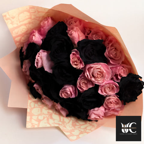 Bouquet of pink and black roses wrapped in peach paper.