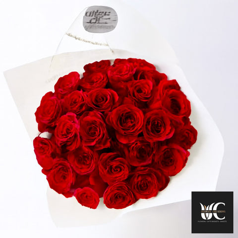 A bouquet of many red roses wrapped in white paper.