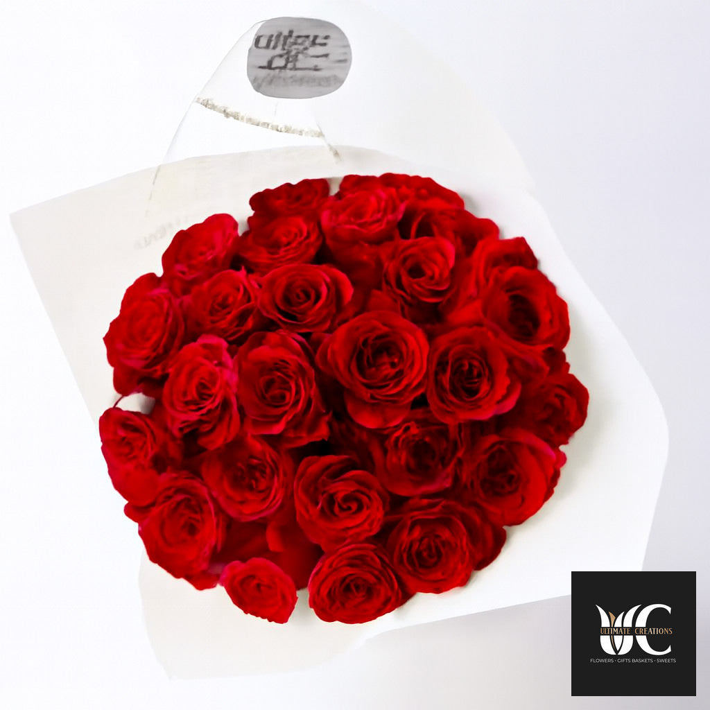 A bouquet of many red roses wrapped in white paper.