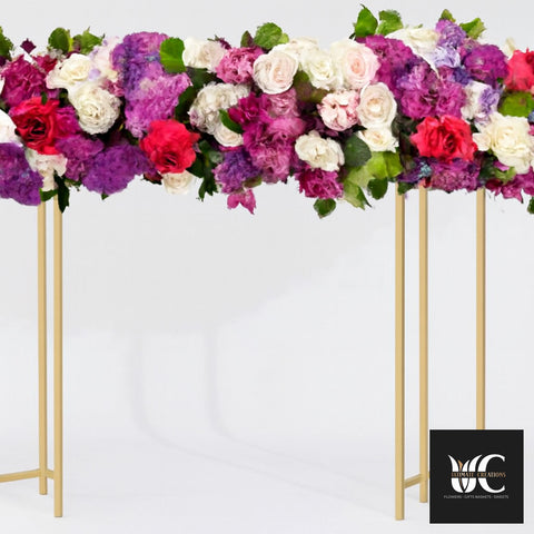 Large floral arrangement of pink, purple, and white flowers on gold metal frames against a white backdrop.