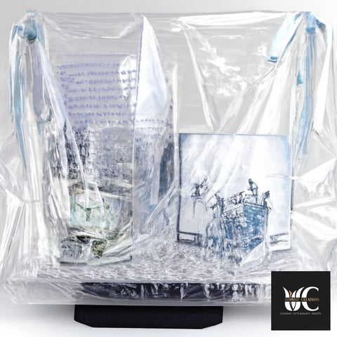 Clear cellophane-wrapped gift arrangement with printed boxes and light blue ribbon accents on a black base.