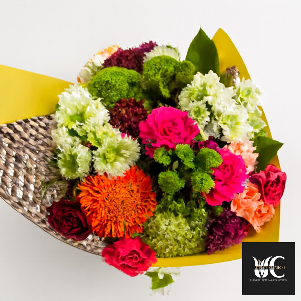 Colorful mixed bouquet with pink, orange, green, white, and burgundy flowers wrapped in yellow paper.