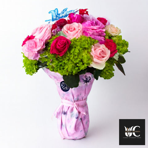 Bouquet of pink and fuchsia roses with green filler, wrapped in pink paper and tied with a ribbon.
