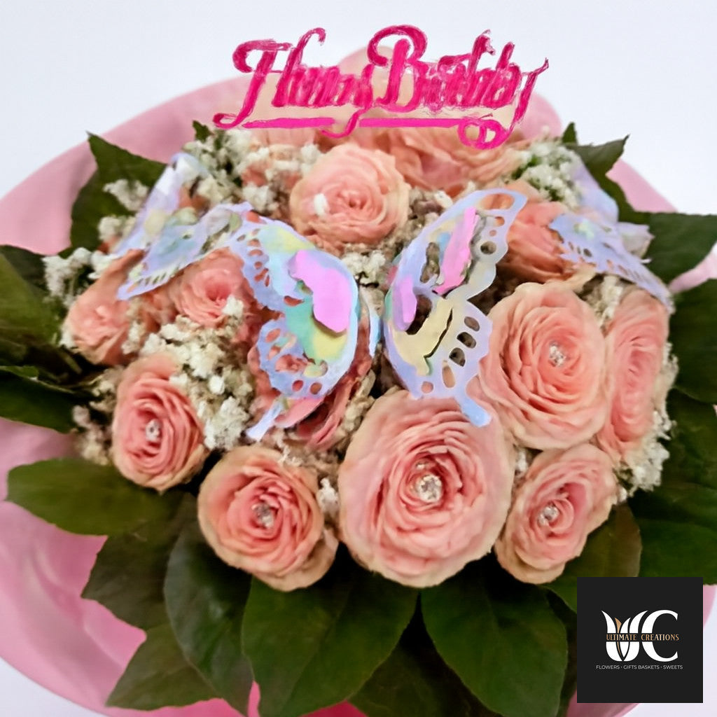 Pink bouquet with layered blooms, baby’s breath, butterfly accents, and a pink topper.