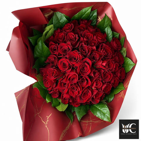 Large bouquet of red roses with lush green leaves wrapped in deep burgundy paper.